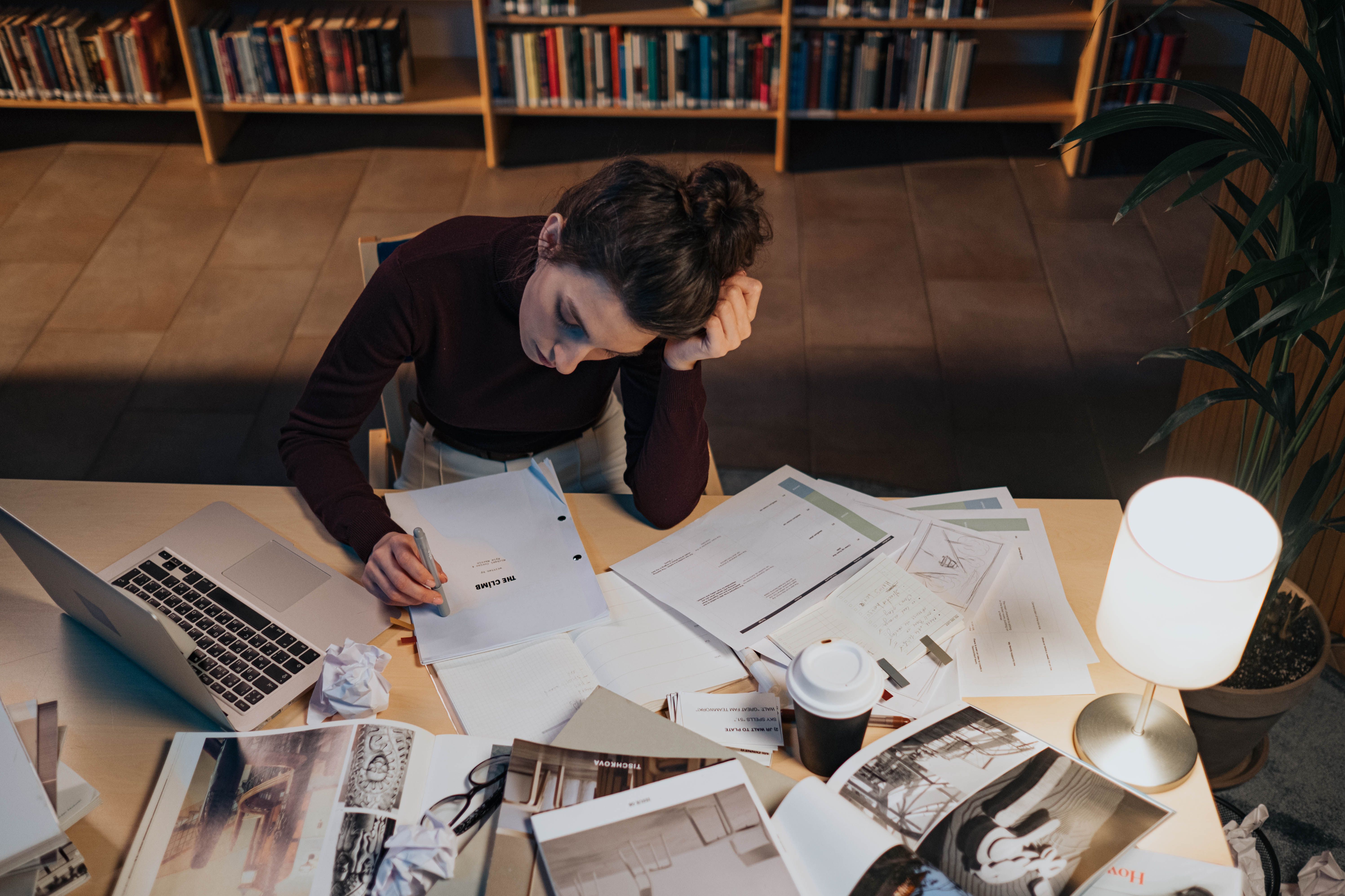 A woman reading and annotating printed script pages at a desk.